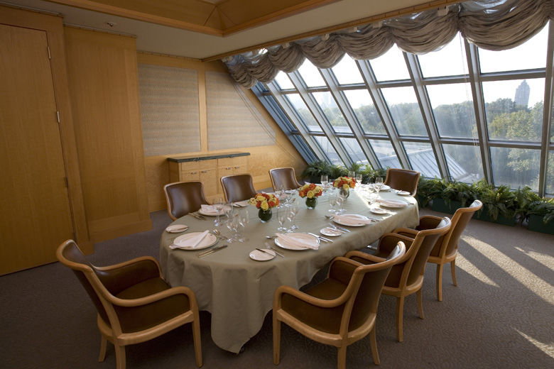 An intimate and elegant room with skylights at the far end; a dining room table and leather arm chairs are set with an elegant casual service