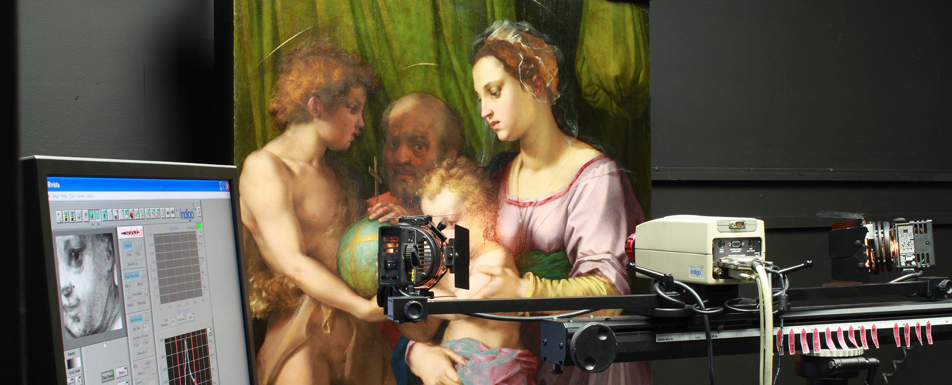 Scientific imaging equipment scan an artwork by Andrea de Sarto. The results of the scan appear on a computer screen to the left of the image.