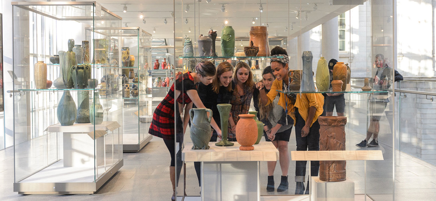 A group of young women gathered around ancient pottery