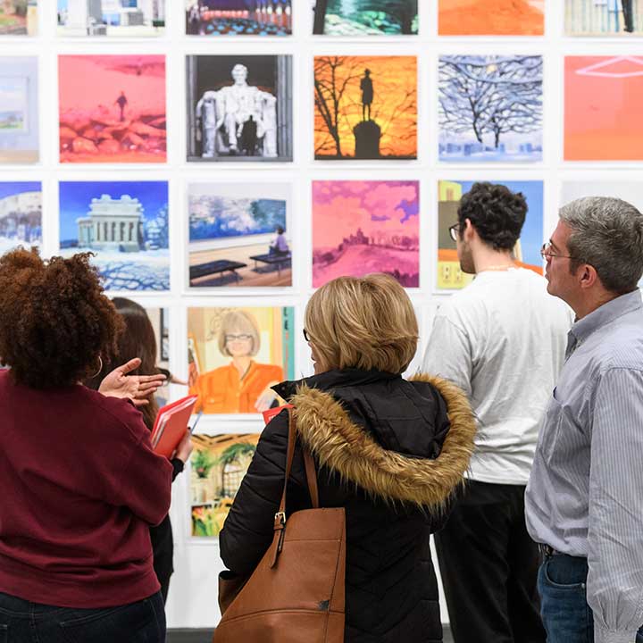 Adults in conversation discussing an artwork in front of them.