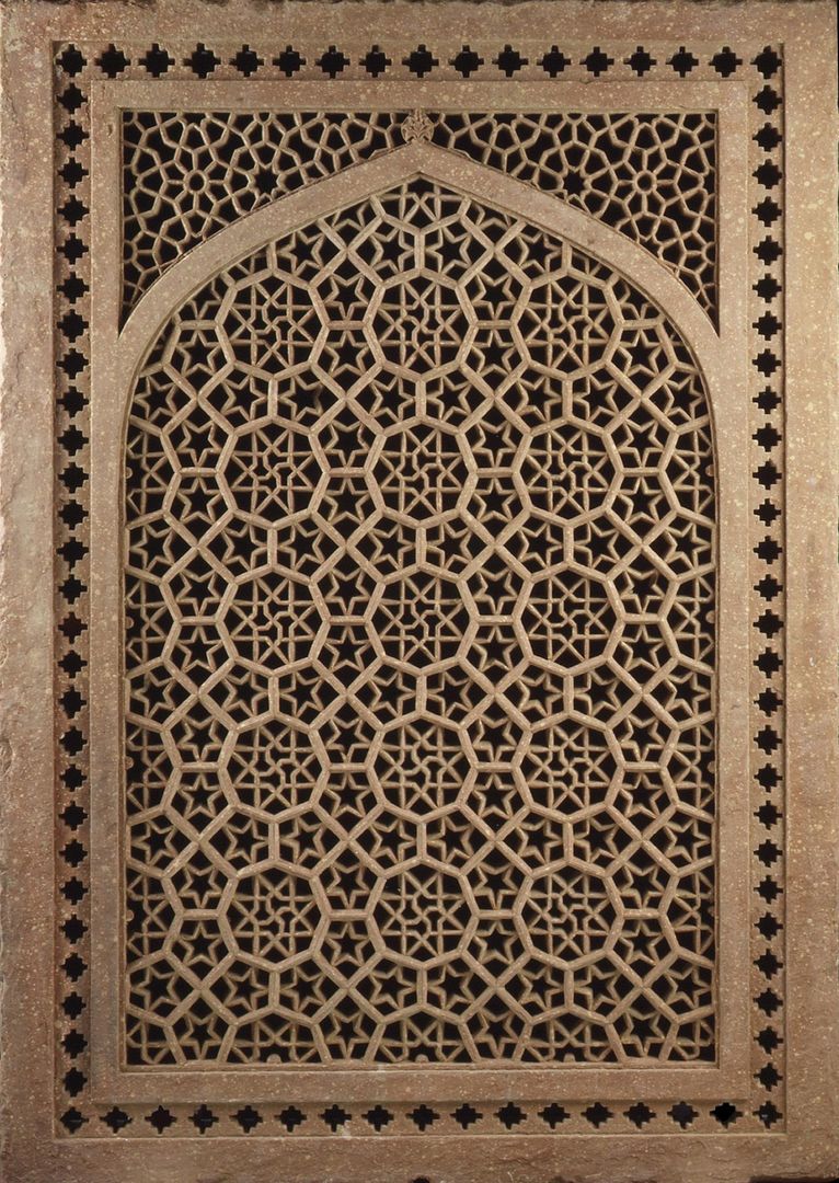 A sandstone window screen, pierced and carved in an intricate geometric pattern