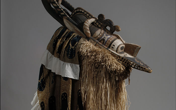 An African mask made of carved and painted wood, fabric, and plant fibers