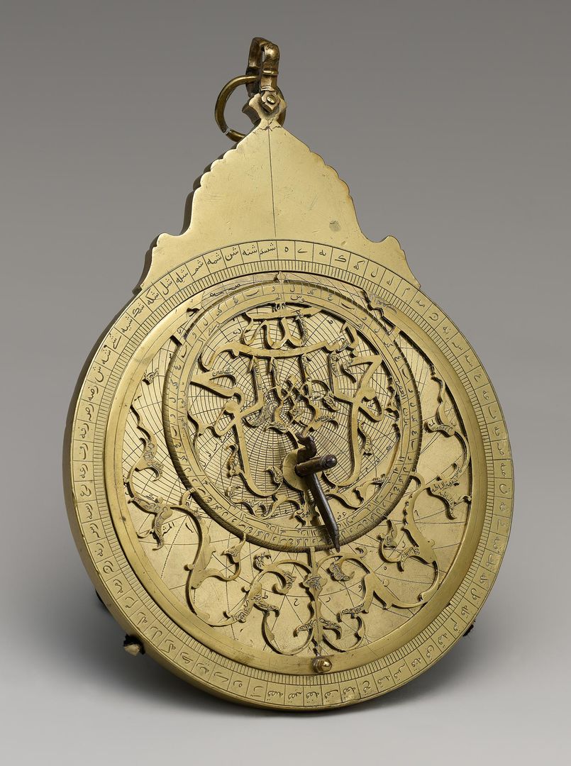 A scientific instrument constructed of brass circular plates placed one on top of the other, which can be slid and rotated; the brass is intricately pierced and engraved with Arabic calligraphy and floral motifs