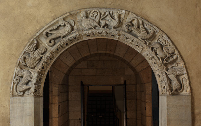 A stone arched doorway with seven fantastic animals carved in relief bordering the arch