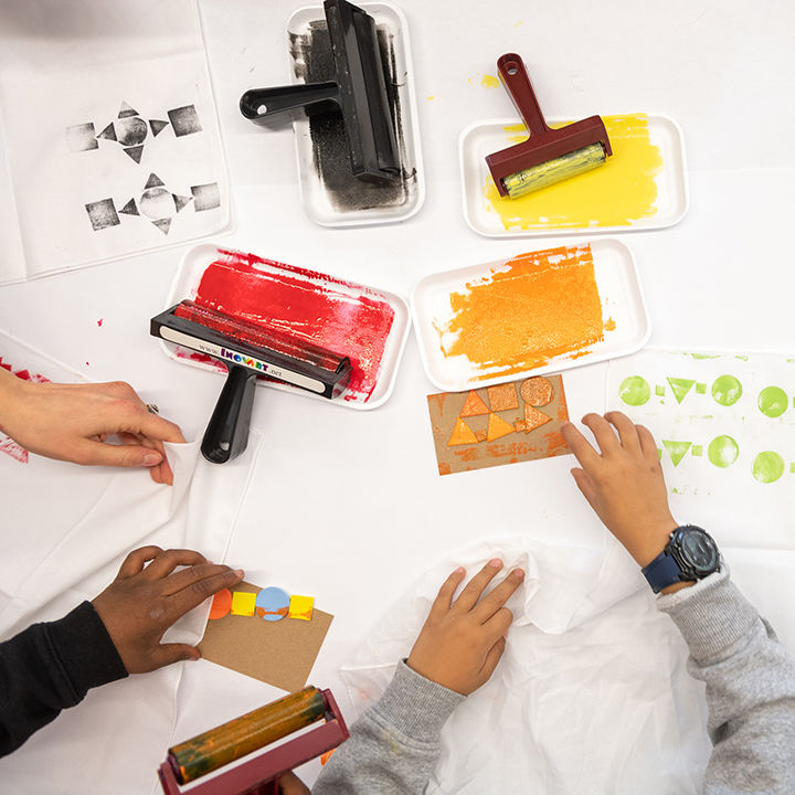 Children's hands making colorful block prints as seen from above.