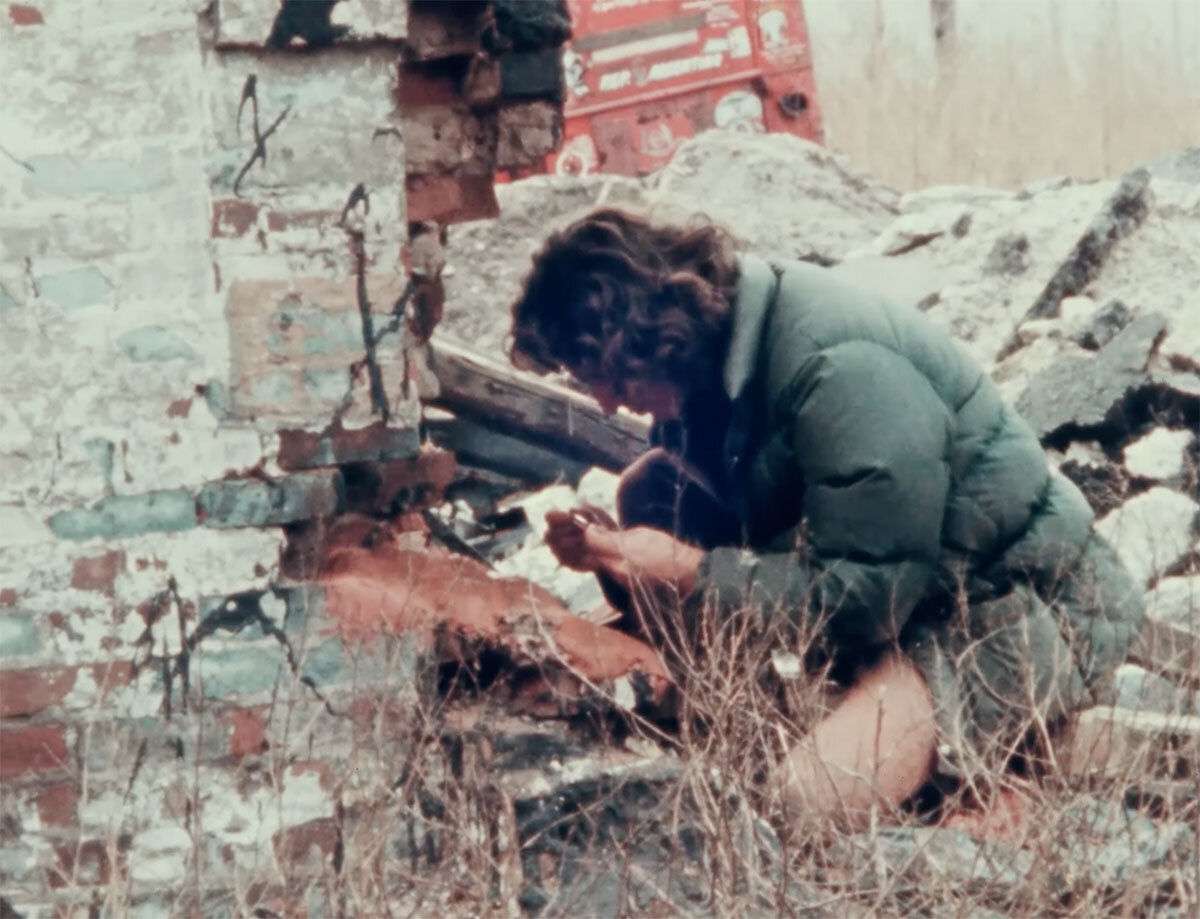 An artist kneels in a tiny village