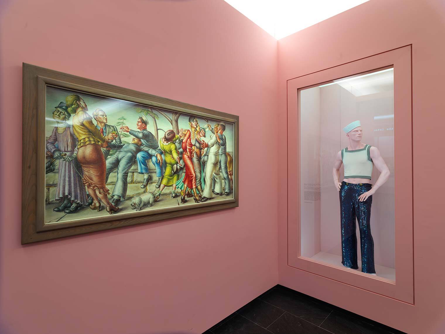 A photograph depicting Cadmus's painting next to a sailor outfit in the exhibition Camp