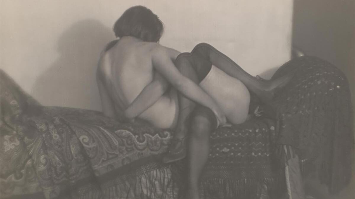 A black and white photograph of two nude women in a loving embrace.