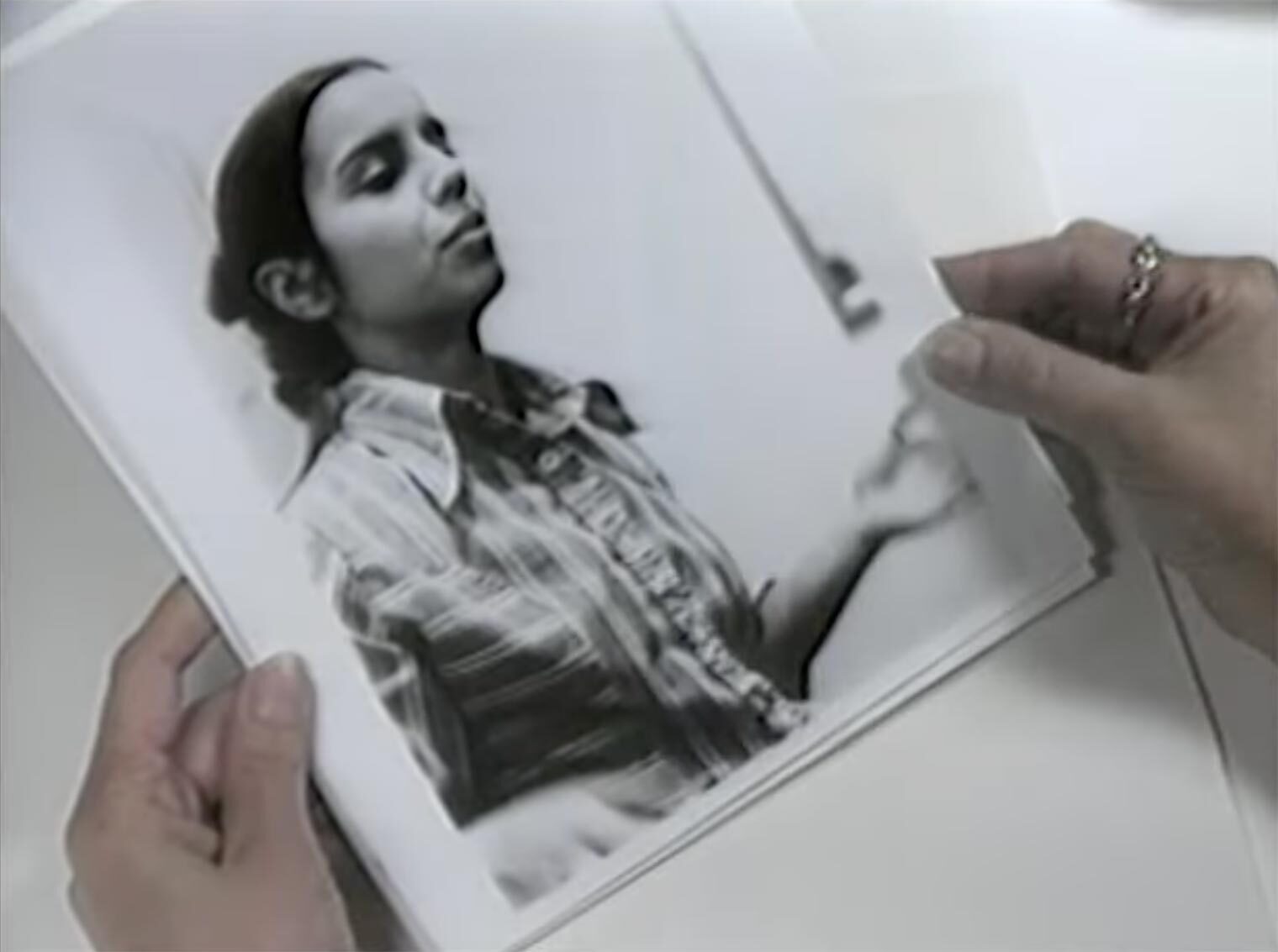 A film still of a person holding a photograph of Mendieta
