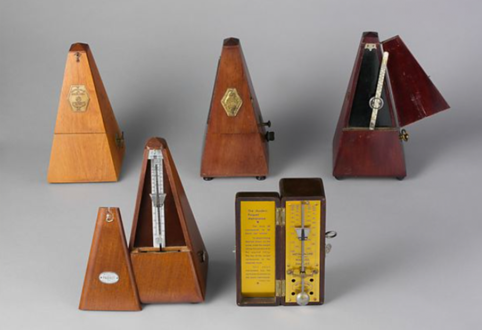 A group of metronomes photographed against a gray background