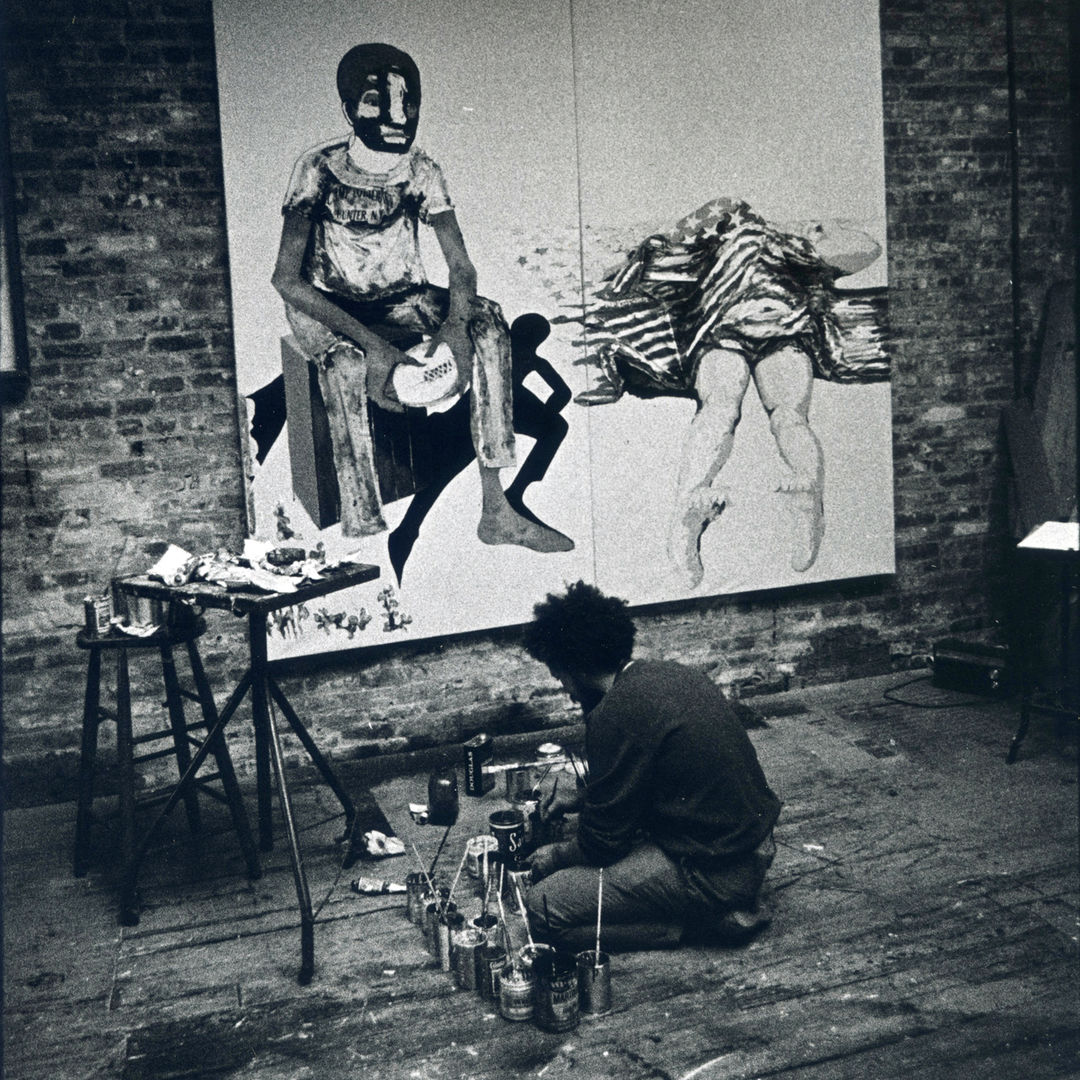 1970 black and white photograph of Benny Andrews working in his studio, back to the camera, facing the painting No More Games in progress.