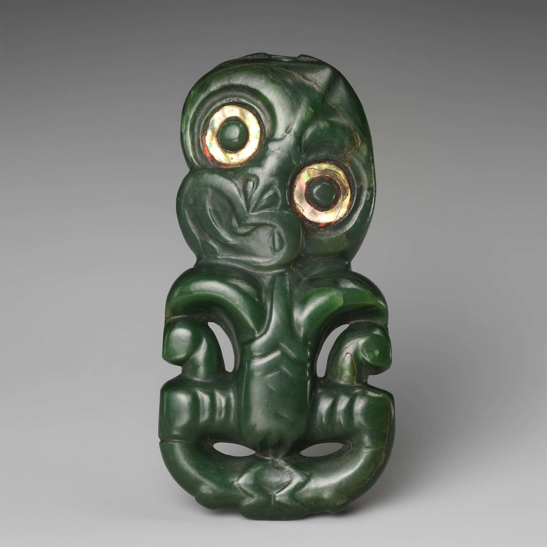 Maori hei tiki, or greenstone pendant, carved with large eyes and abstracted human facial features, embryonic quality