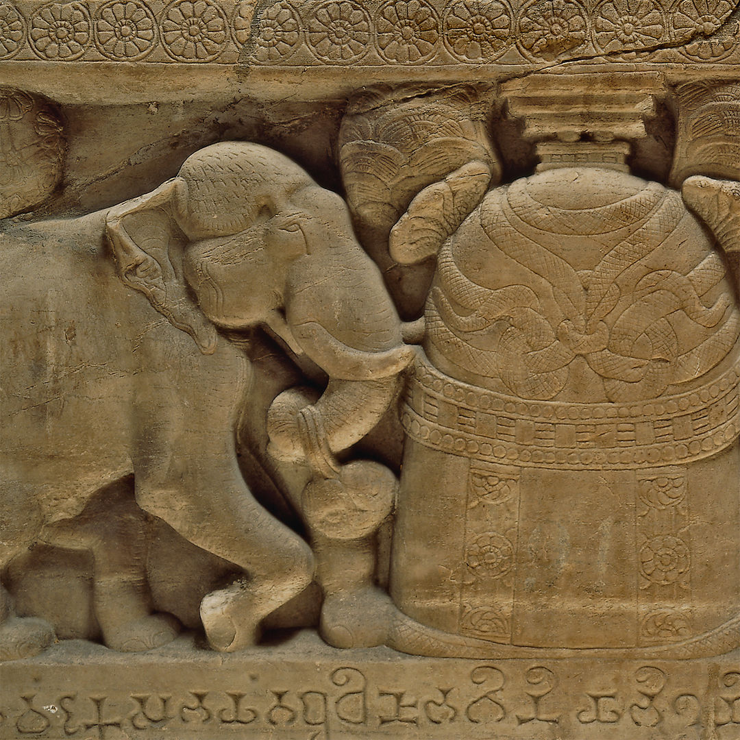 Limestone carving of an elephant next to a stupa encircled with snakes