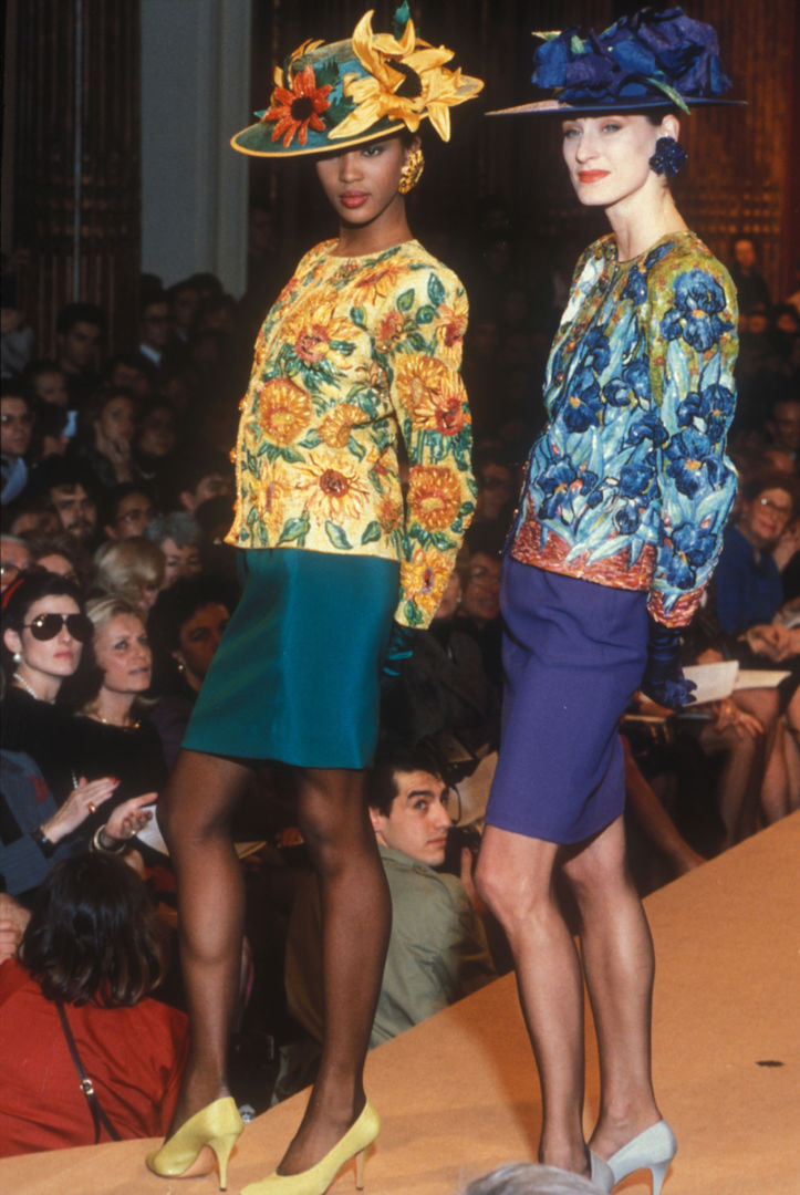 Runway image of Naomi Campbell wearing Yves Saint Laurent's Sunflower jacket next to a model wearing the Iris jacket