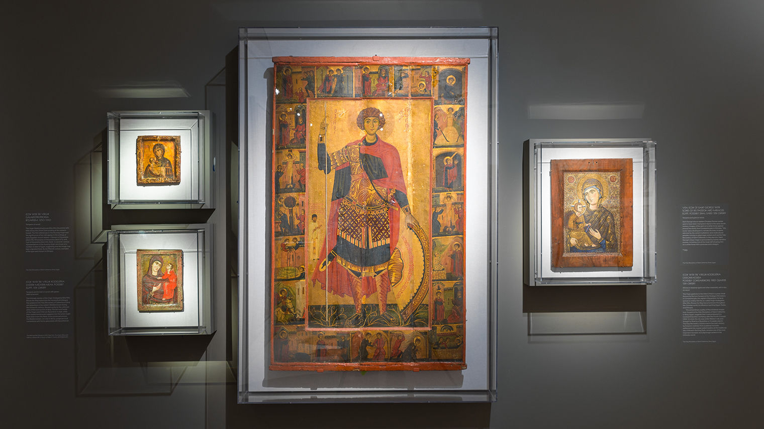 Shot of four Byzantine icon paintings hung in a gallery with a dark gray background.