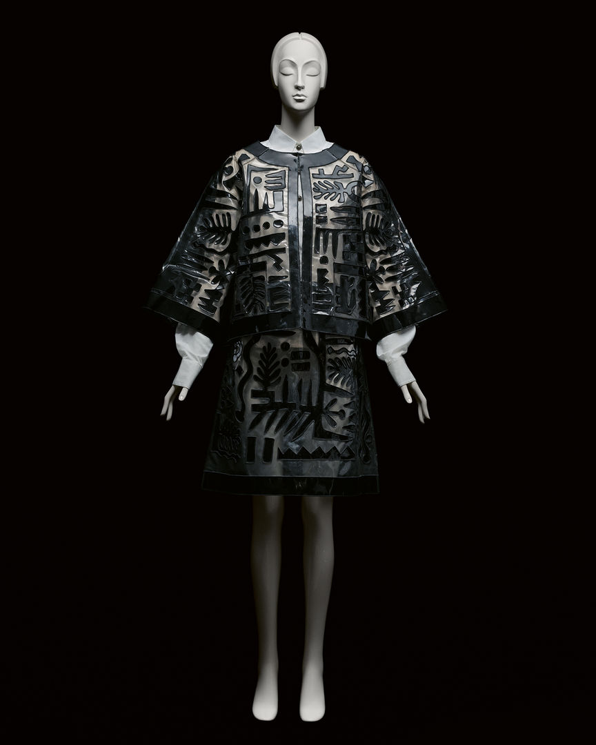 A black dress fitted on a full body white mannequin in dramatic lighting against a pitch black background. 