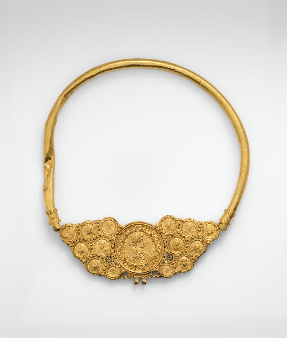 a gold pectoral with coins and a pseudo-medallion that holds fourteen gold coins and two gold discs that are linked together and held by a large gold tube surrounding it. 
