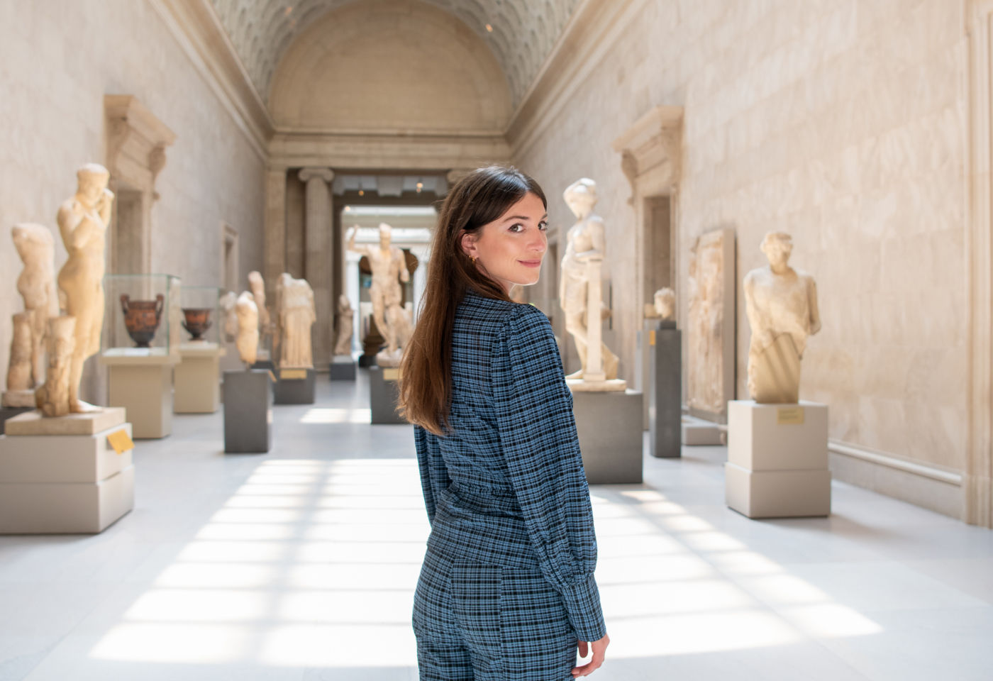 Katy Hessel stands in the sunlit Greek and Roman galleries at The Met Museum.