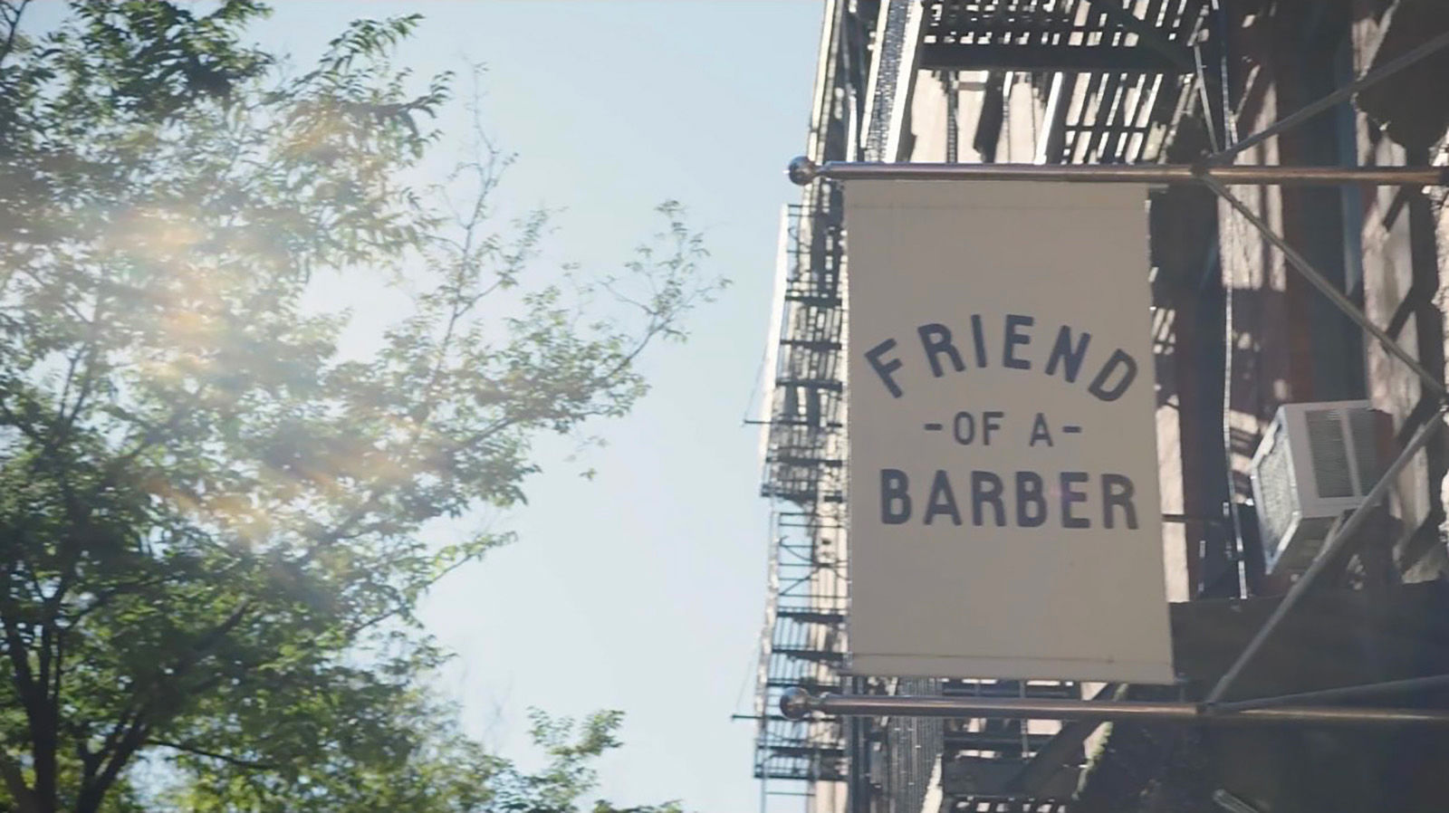 White sign with blue letters that reads "Friend of a Barber."