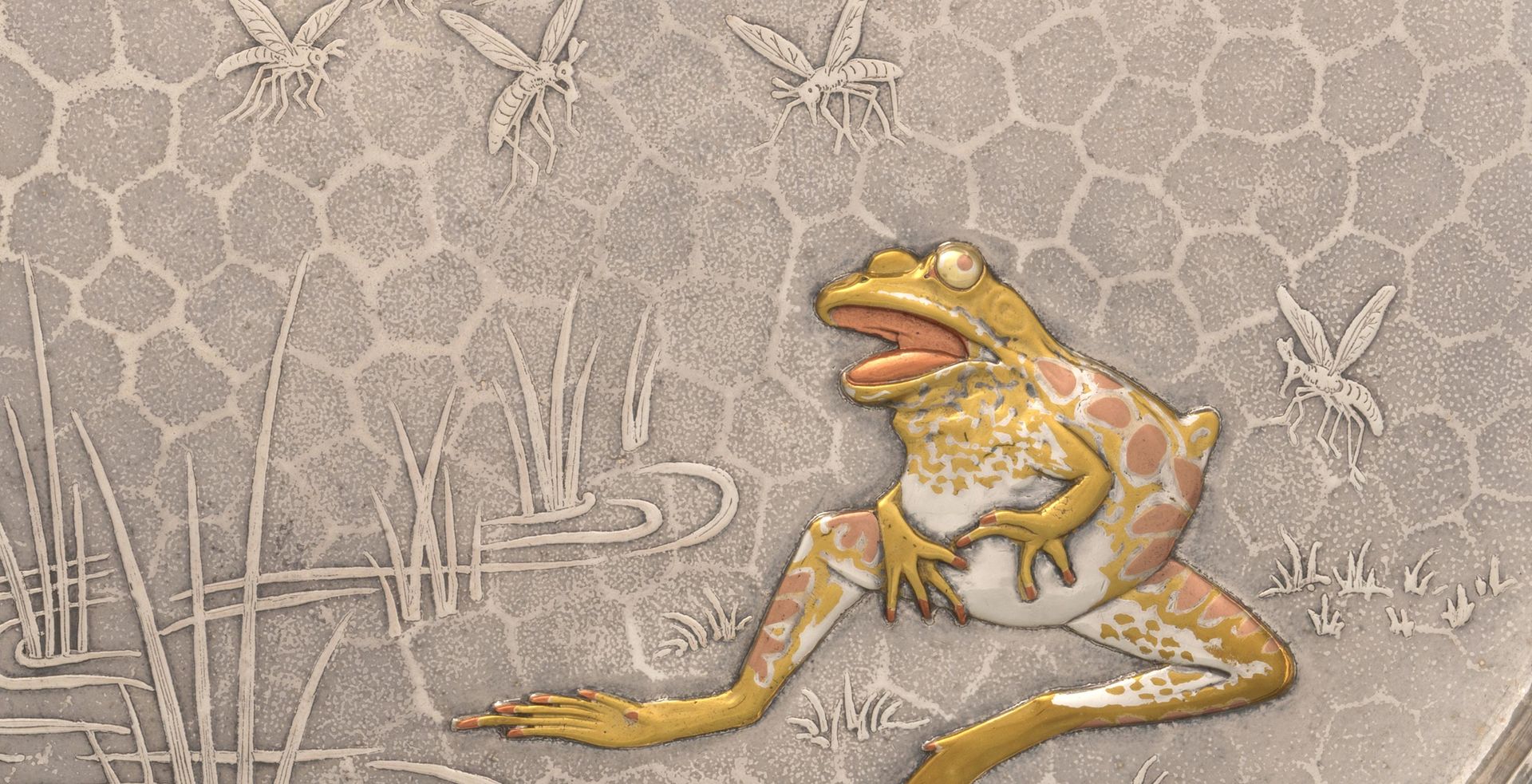 Detail of a silver tray featuring the design of a frog seated at the edge of a grassy pond with a queue of mosquitos approaching from a setting sun on the horizon. The surface has a hexagonal-shaped texture. The grass and mosquitoes protrude in a low relief on the tray surface. The front is more heavily sculpted and plated with mixed metals that are silver, gold, and copper in tone.