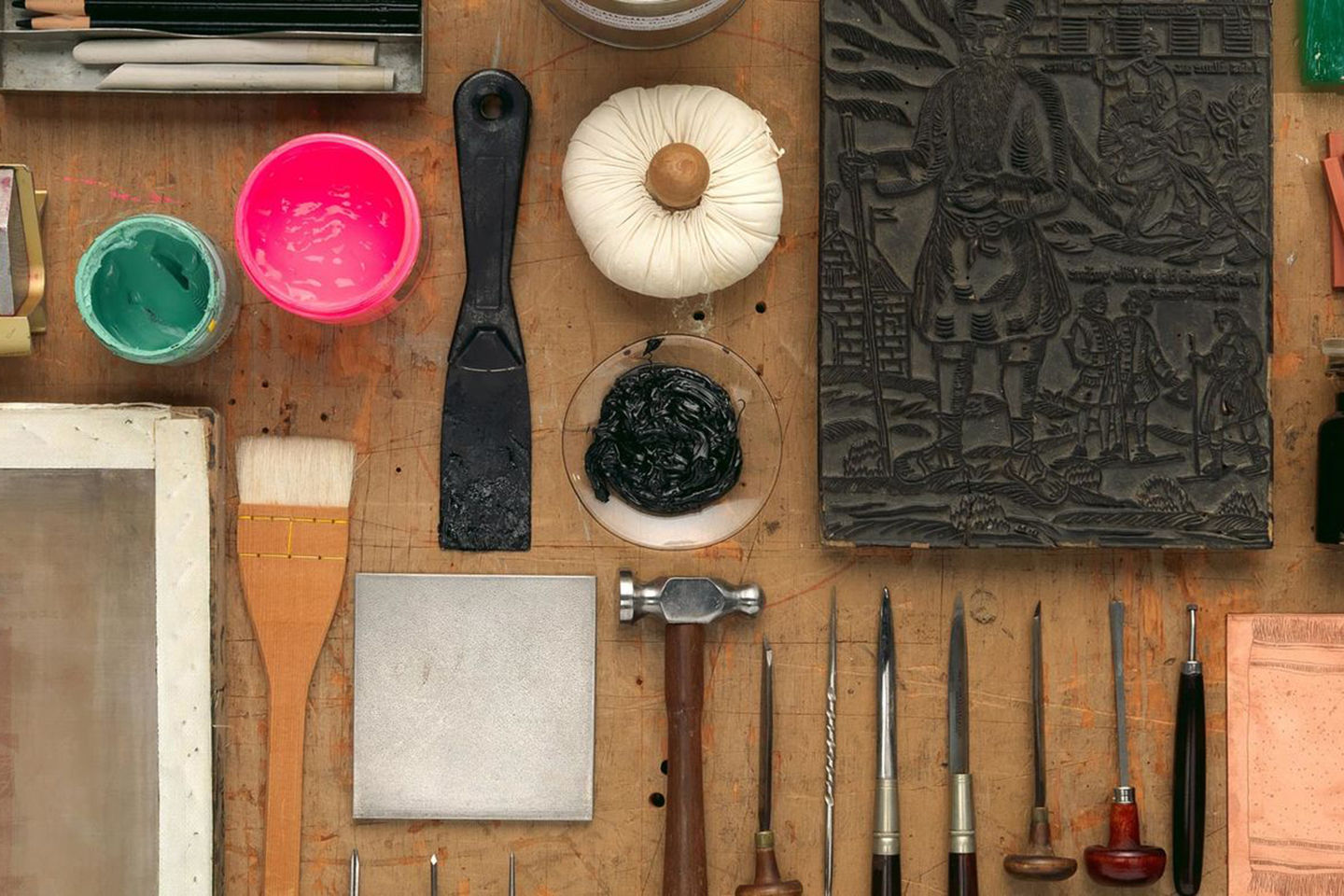 A table set with a neat arrangement of various printmaking materials and tools.