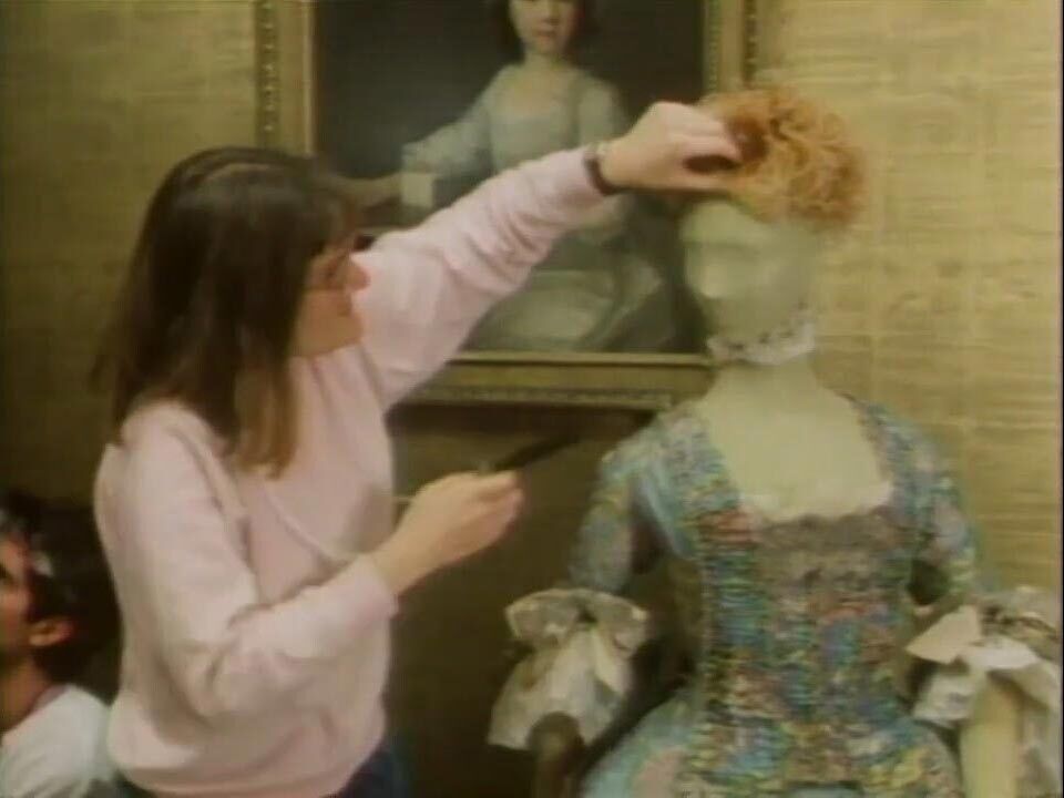 An old photo of a woman dressing a manequin