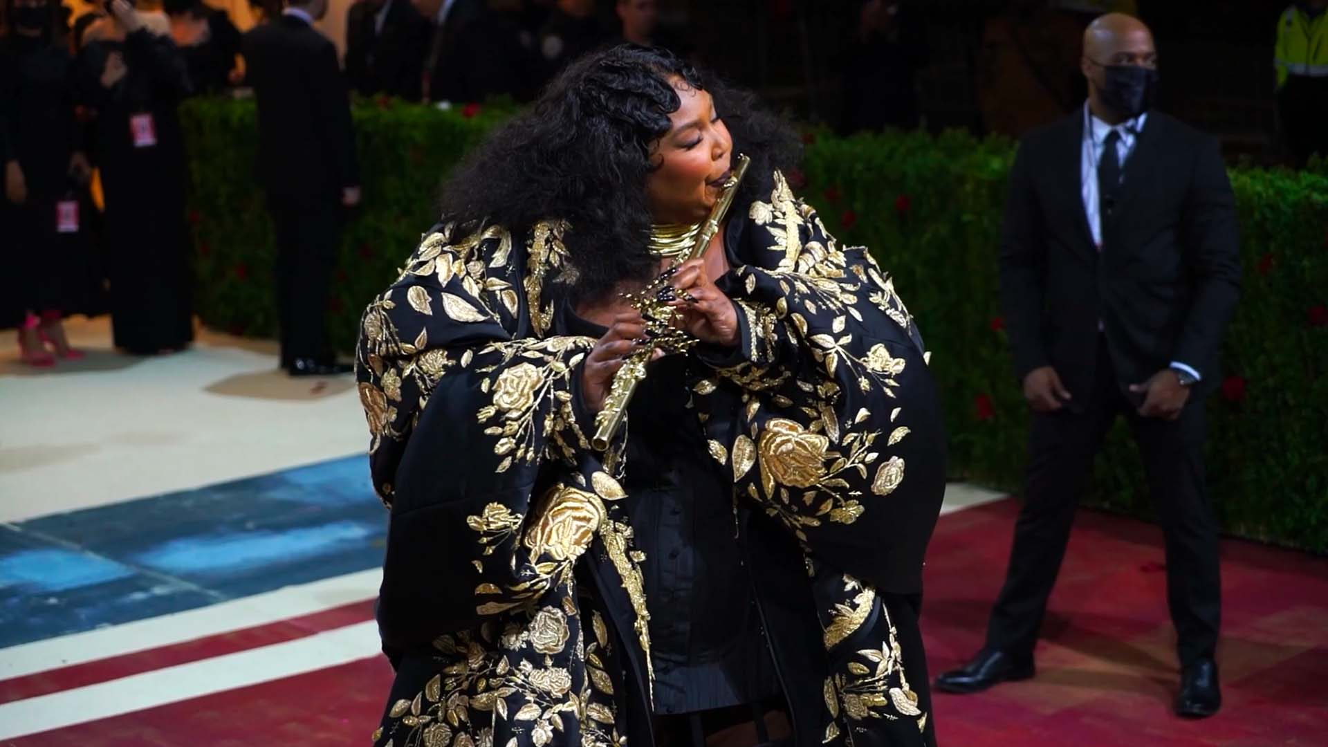 Artist Lizzo plays a flute at the 2022 Met Gala red carpet.
