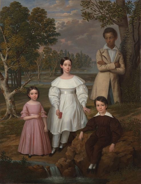 A young black boy leans against a tree behind three white children in formal dress sit. They are all surrounded by the woods and nature.