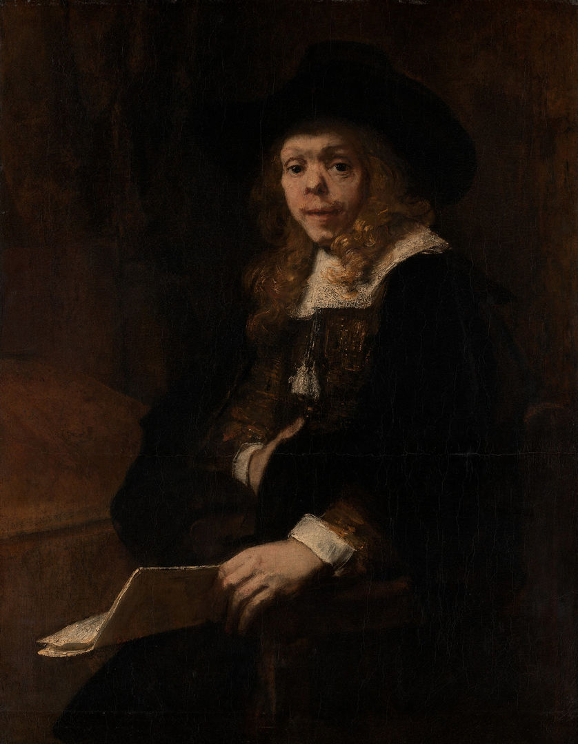 A young man poses for his portrait in a dark room illuminated by a beam of light. His face is noble but disfigured and his hold a book in the light.
