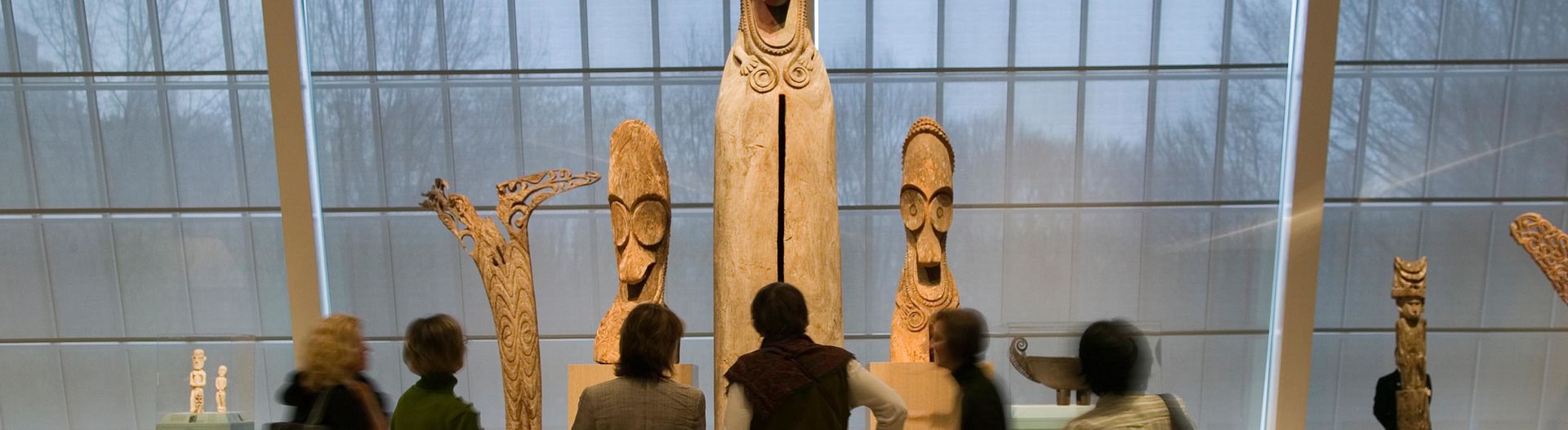 Group in gallery looking at wooden Oceanic sculptures