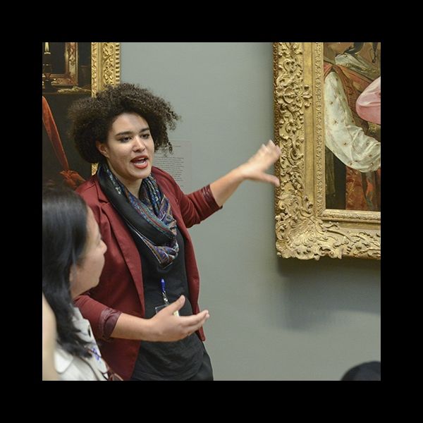 A docent stands before an artwork and explains it to a crowd