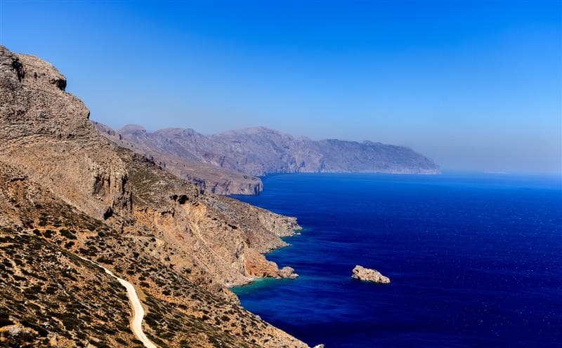 An image of a coastline featuring bright blue water and rocky cliffsides.