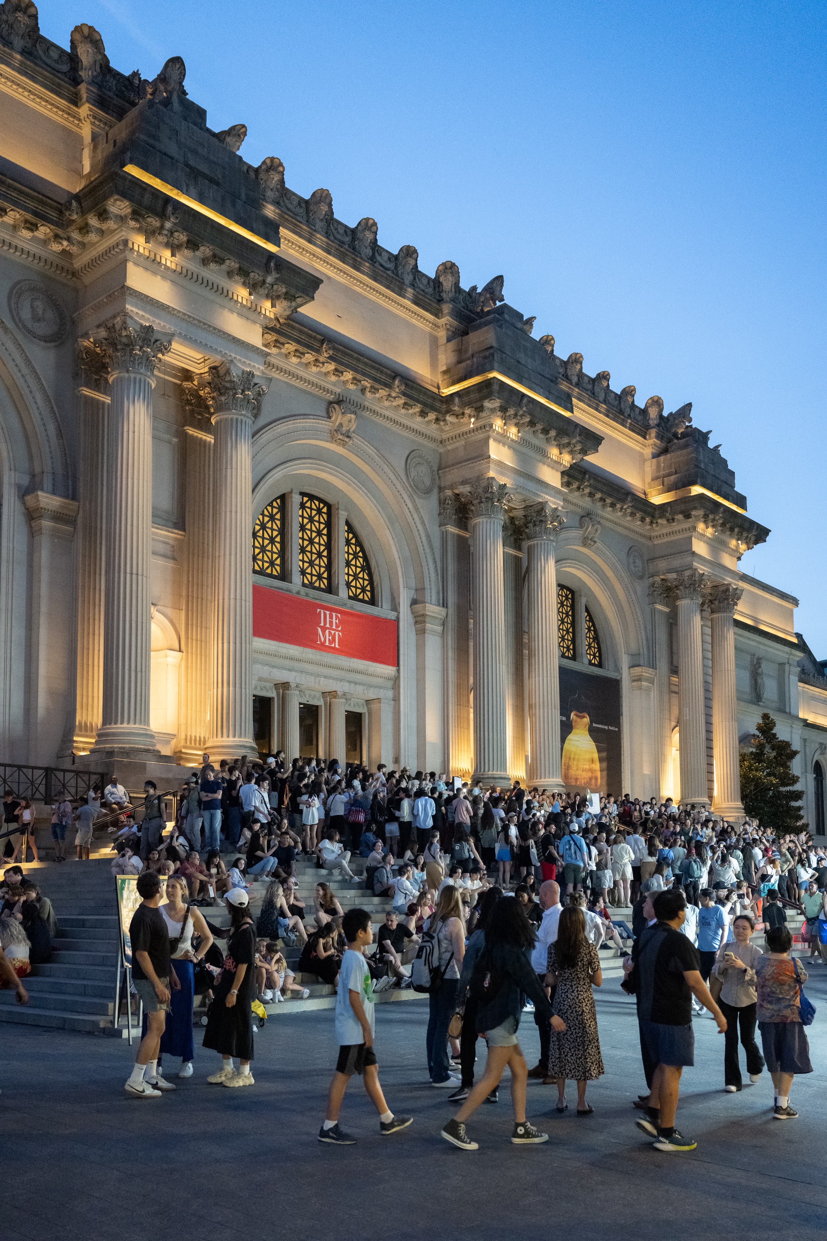 Visitors sit and stand on the steps of The Met on a summer evening at the Museum Mile Festival.