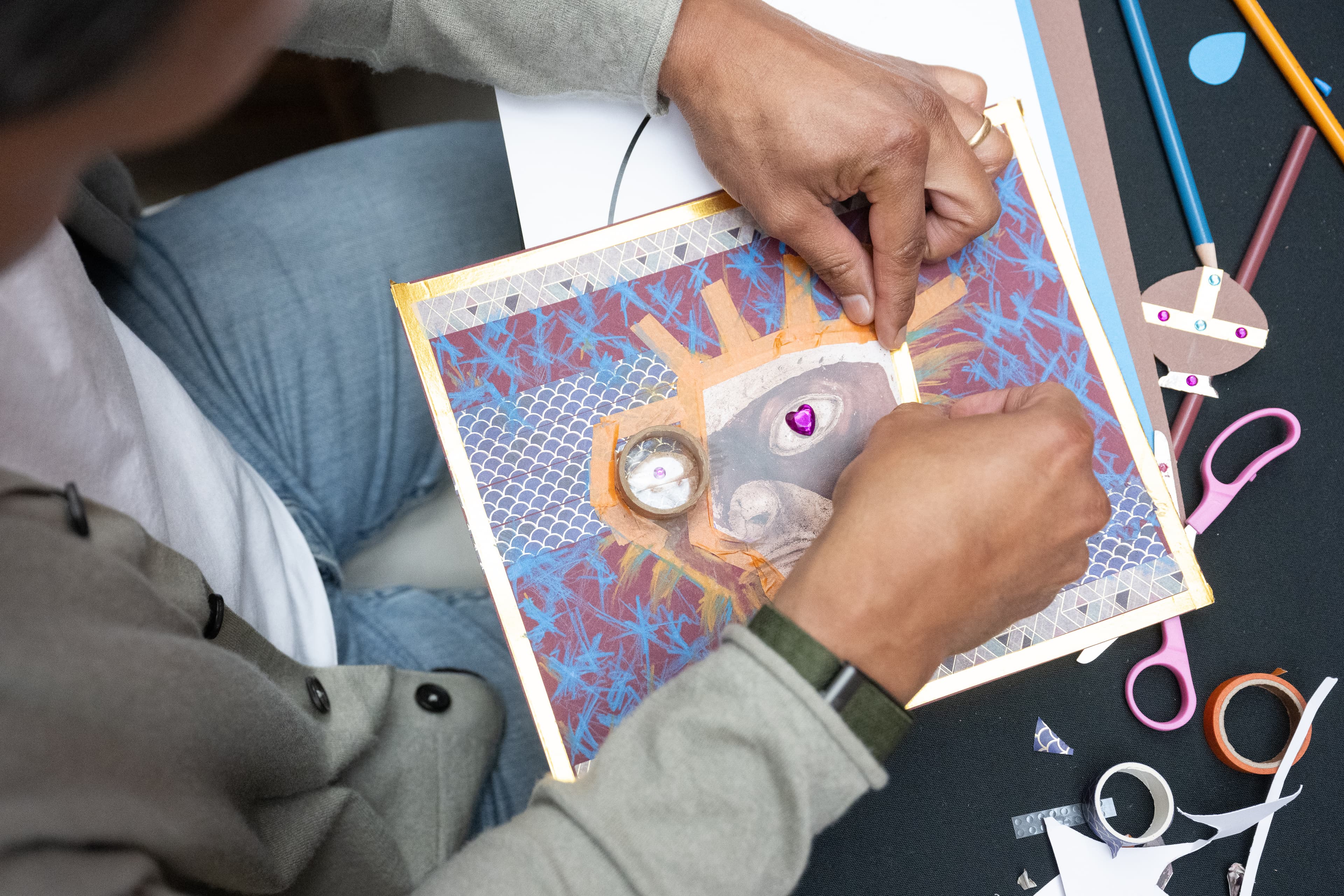 Image of hands working on a colorful paper collage