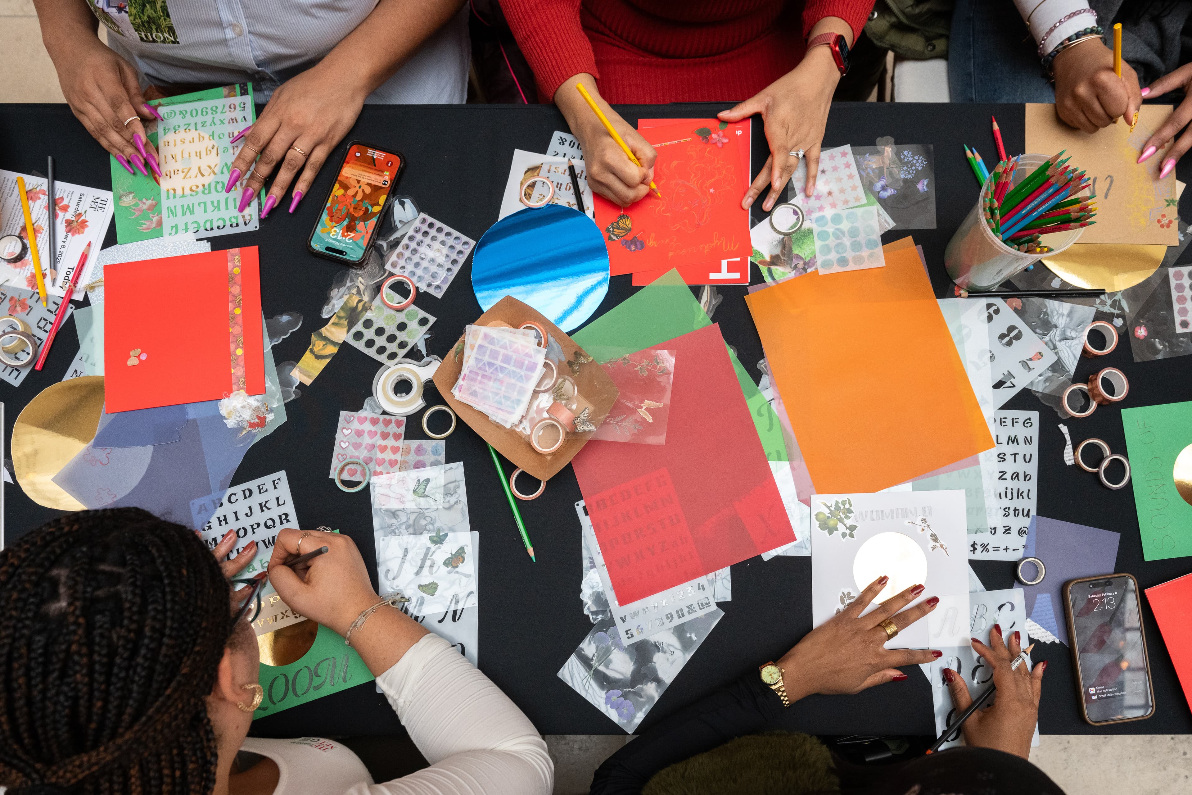 Hands of program participants arranging elements of a collage.