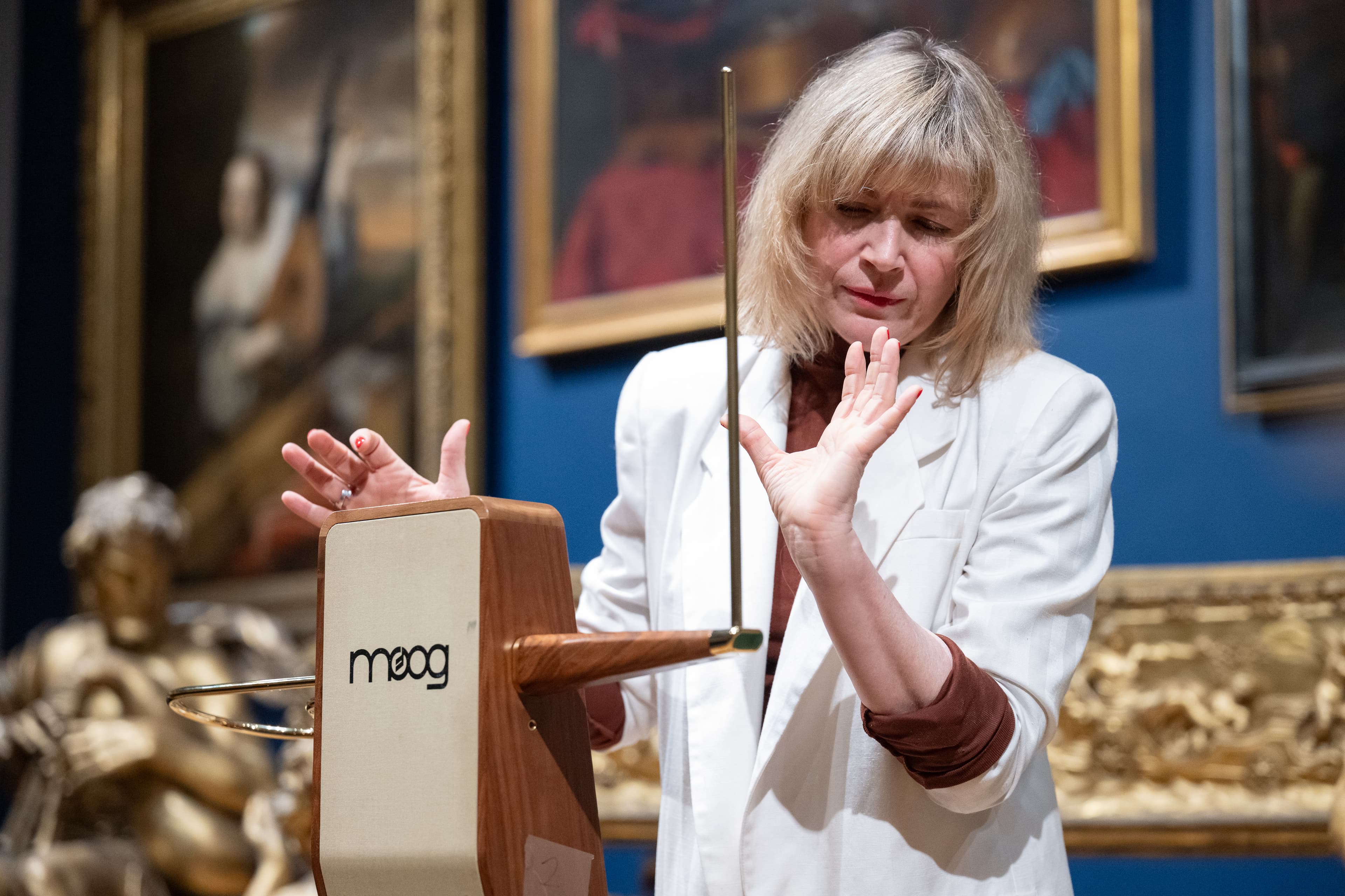 Dorit Chrysler wearing a white jacket playing the theremin. 