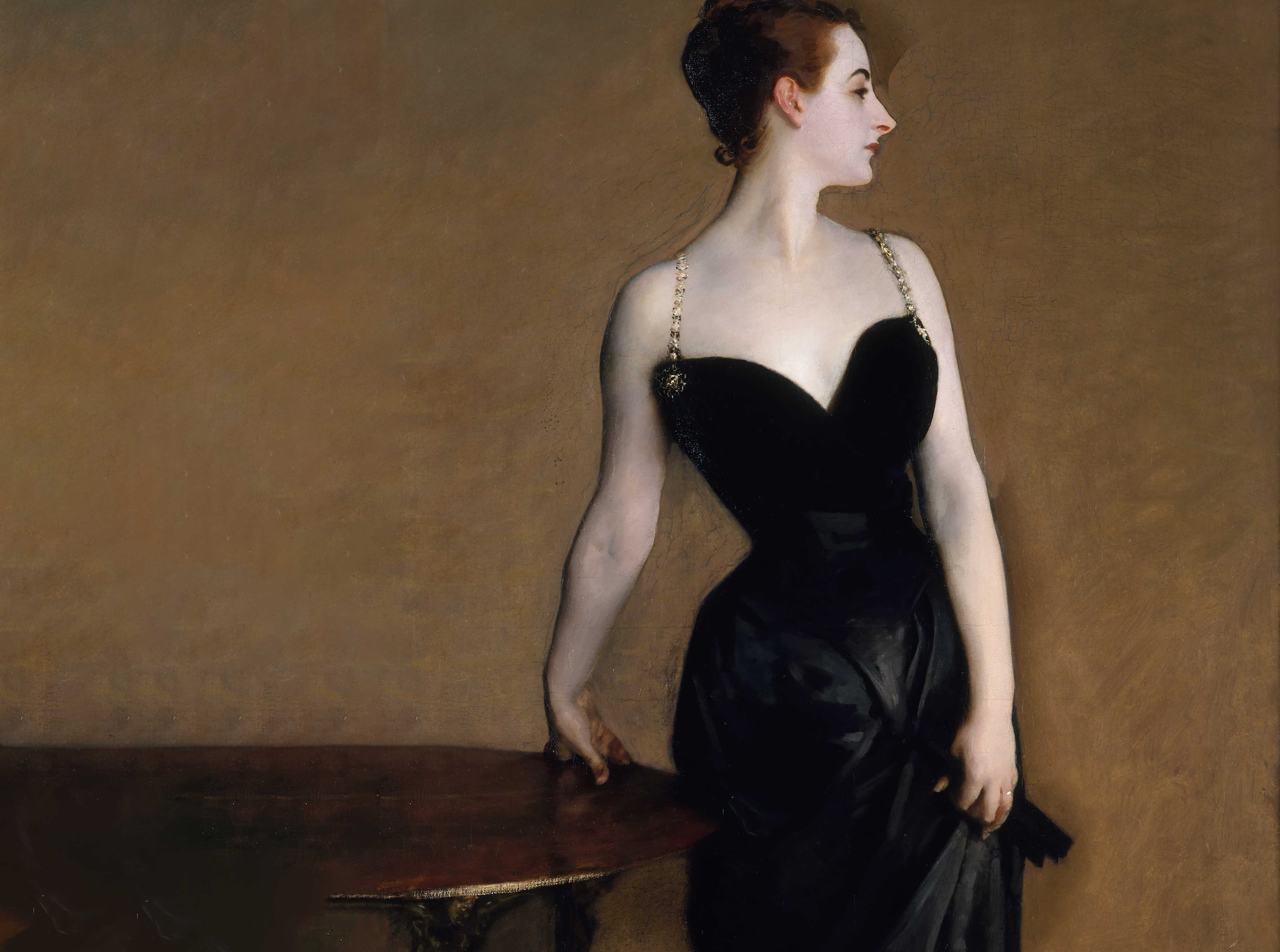An oil painting depicting a pale=skinned, elegant lady wearing a black dress, cinched at the waist and low cut at the bust. Two delicate gold-colored straps suspend the dress. The lady leans on the fingers of her right hand on a table and cinches the skirt of her dress with her left hand. Her face is in profile.