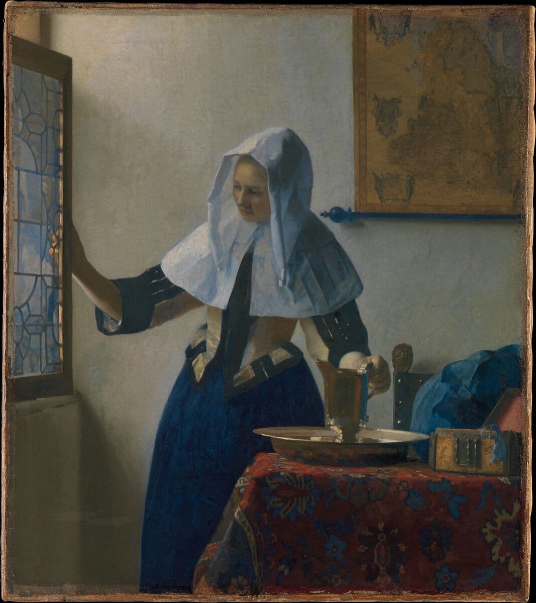A painting of a domestic interior with a woman standing next to an open window. She is wearing a white linen covering protecting her dress and hair, over a blue dress. Her right hand is on the open window and her left hand is on the handle of a water pitcher which is resting on a table.