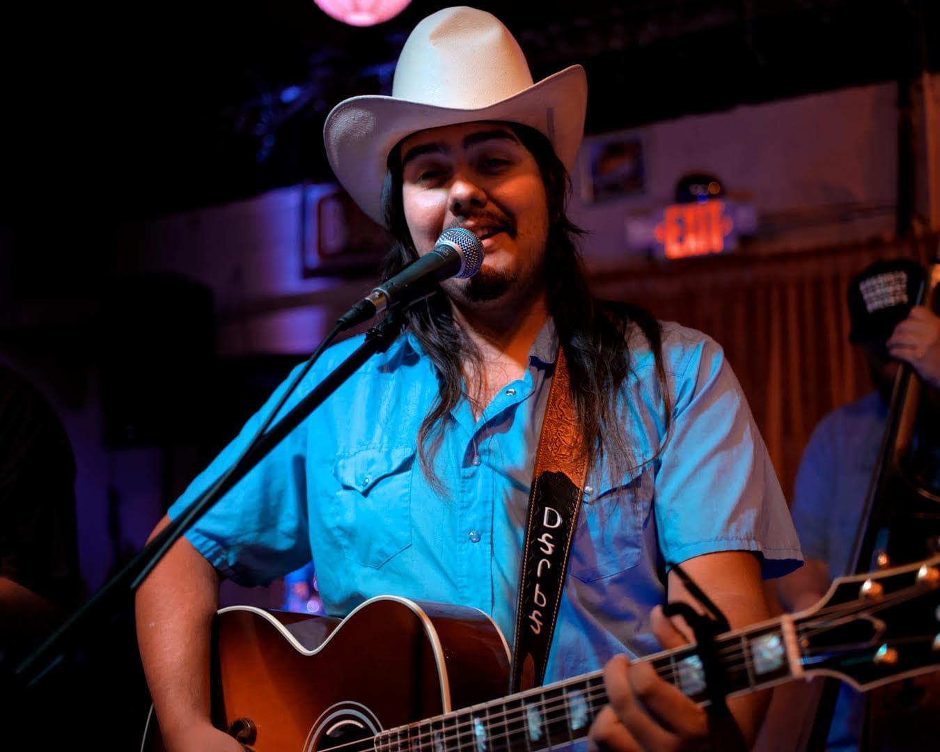 Close up of Mackey singing and playing his guitar. 