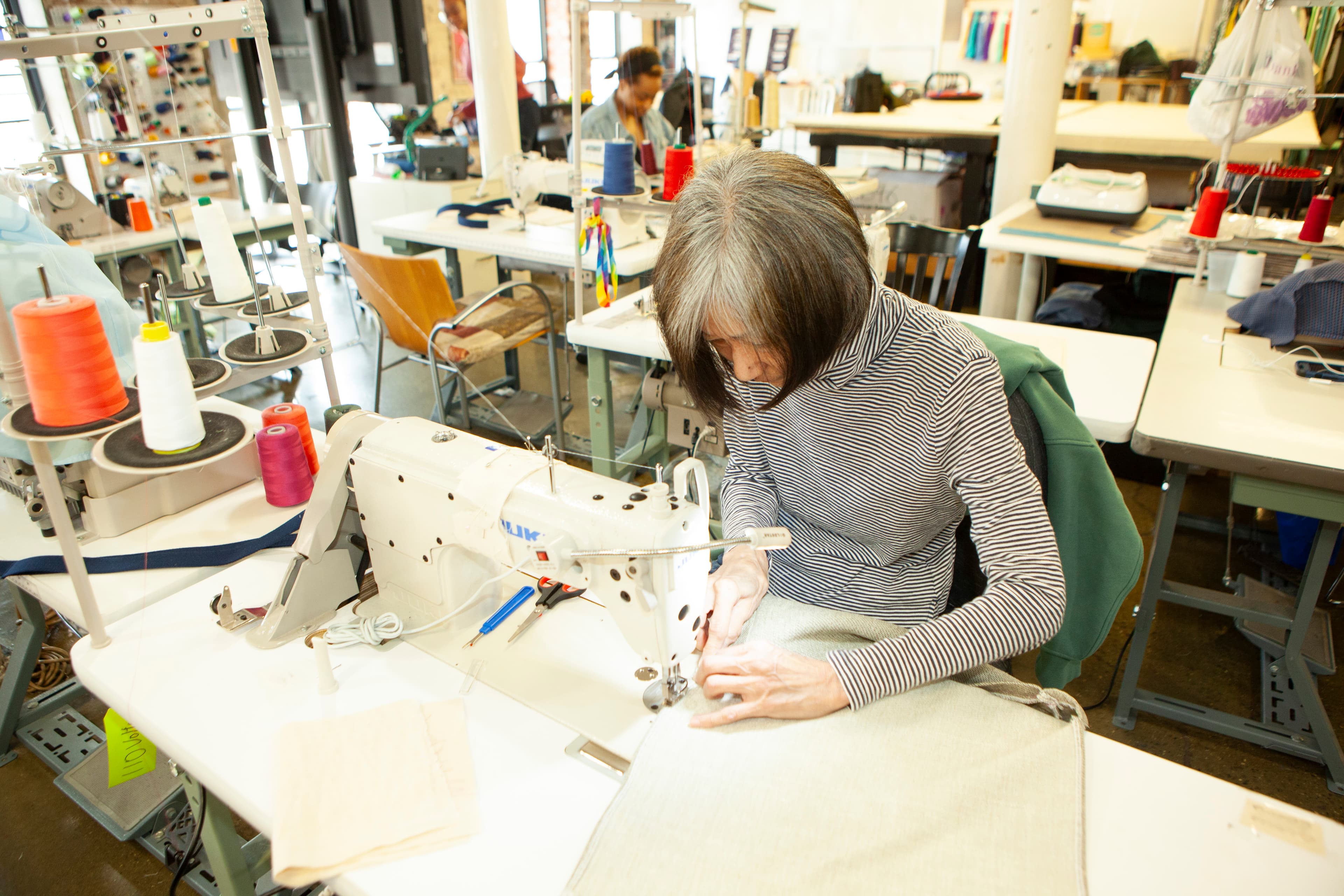 Person sewing fabric on a sewing machine.