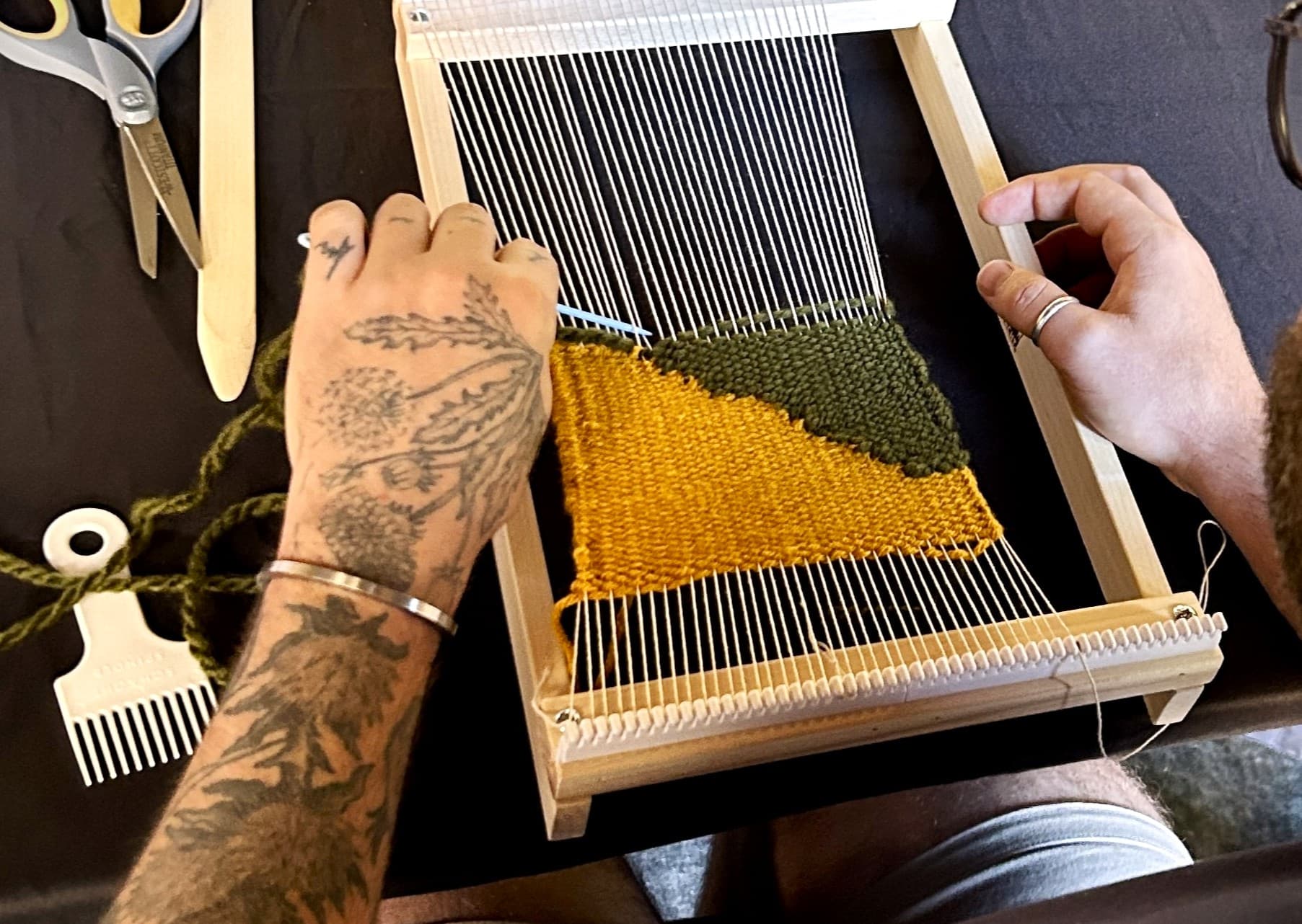 A close up of a hands working on a small tapestry loom