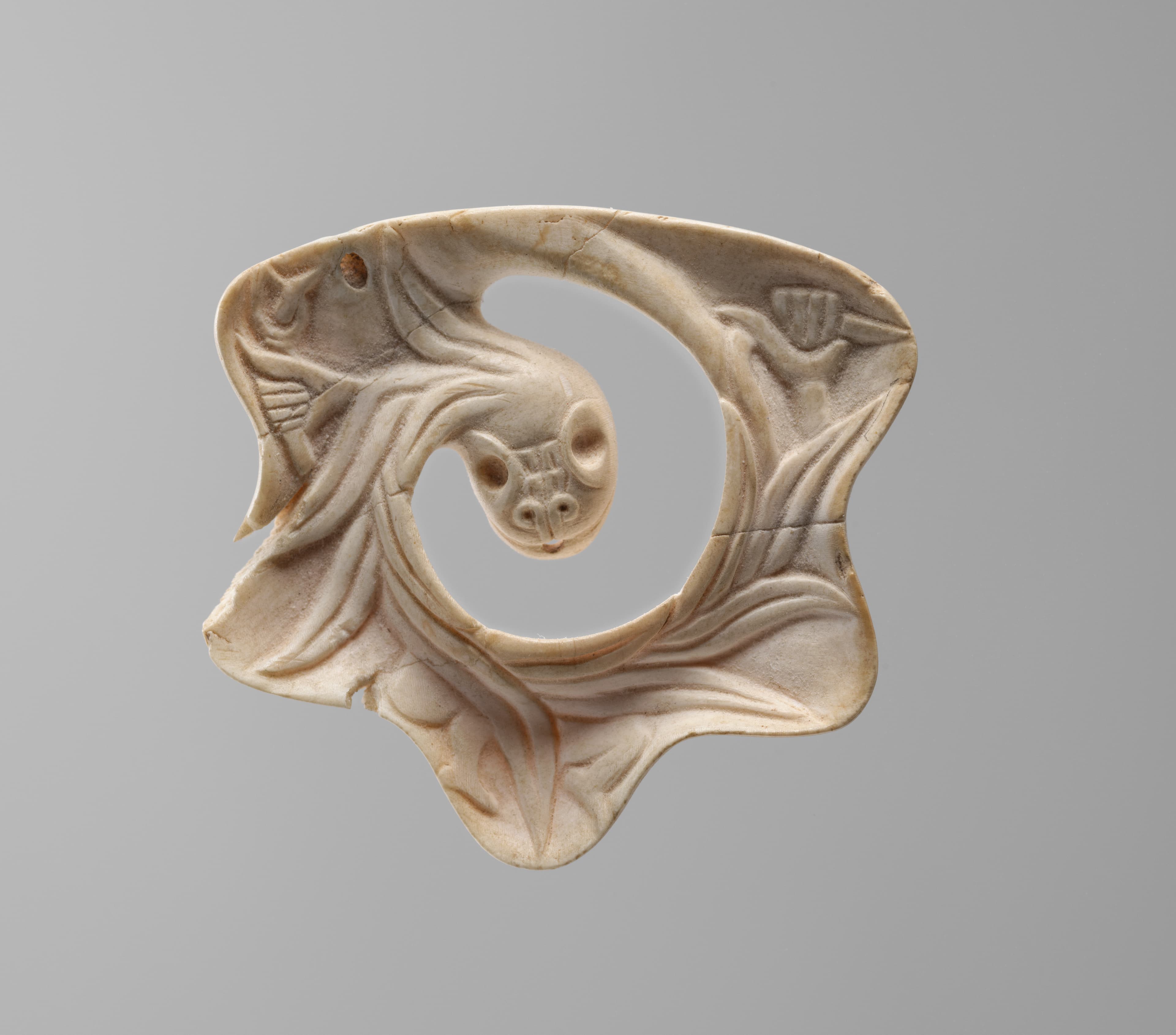 small shell object in the shape of a curling feathered serpent