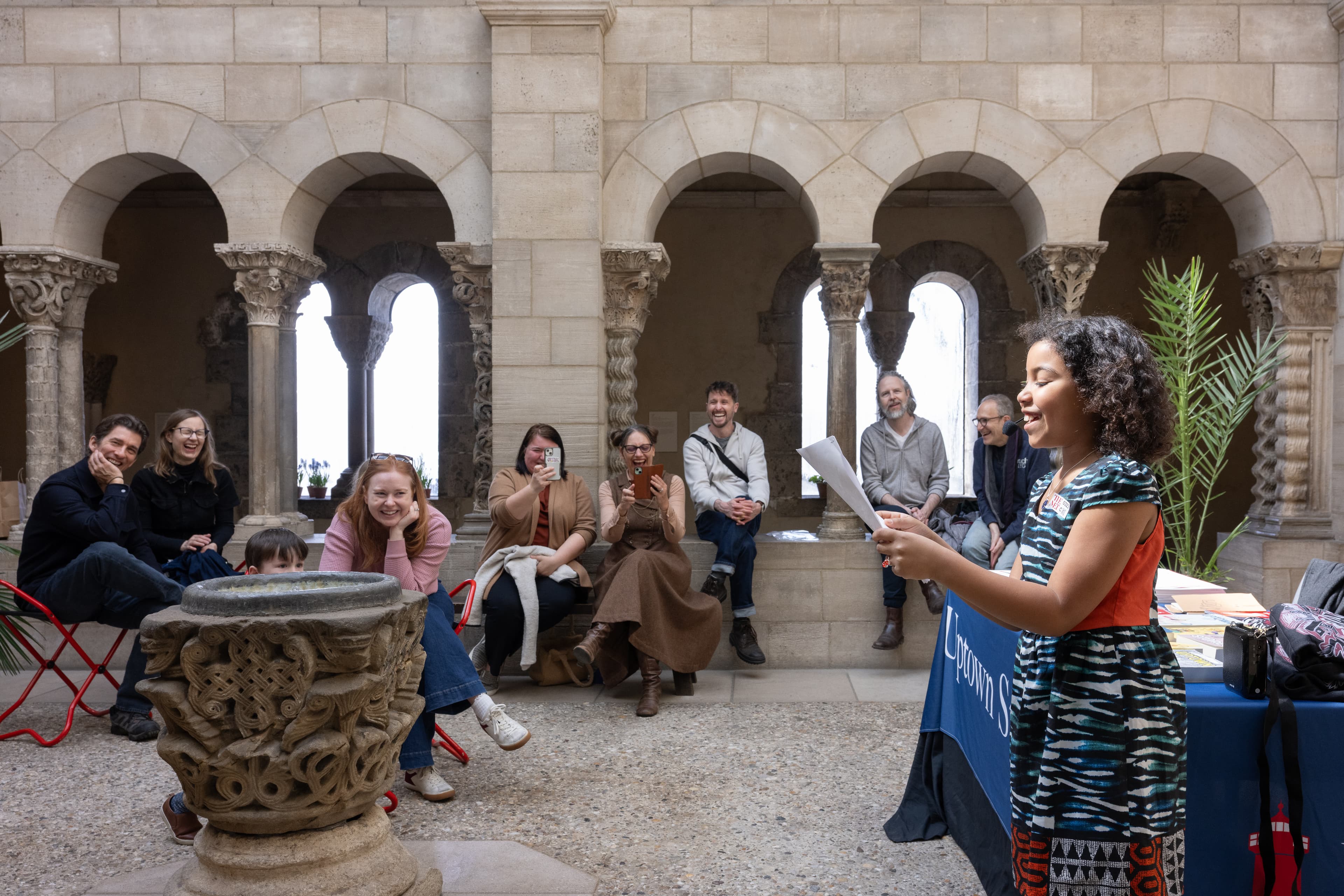 A young person dressed in colorful clothes reading a poem aloud in front of an audience.