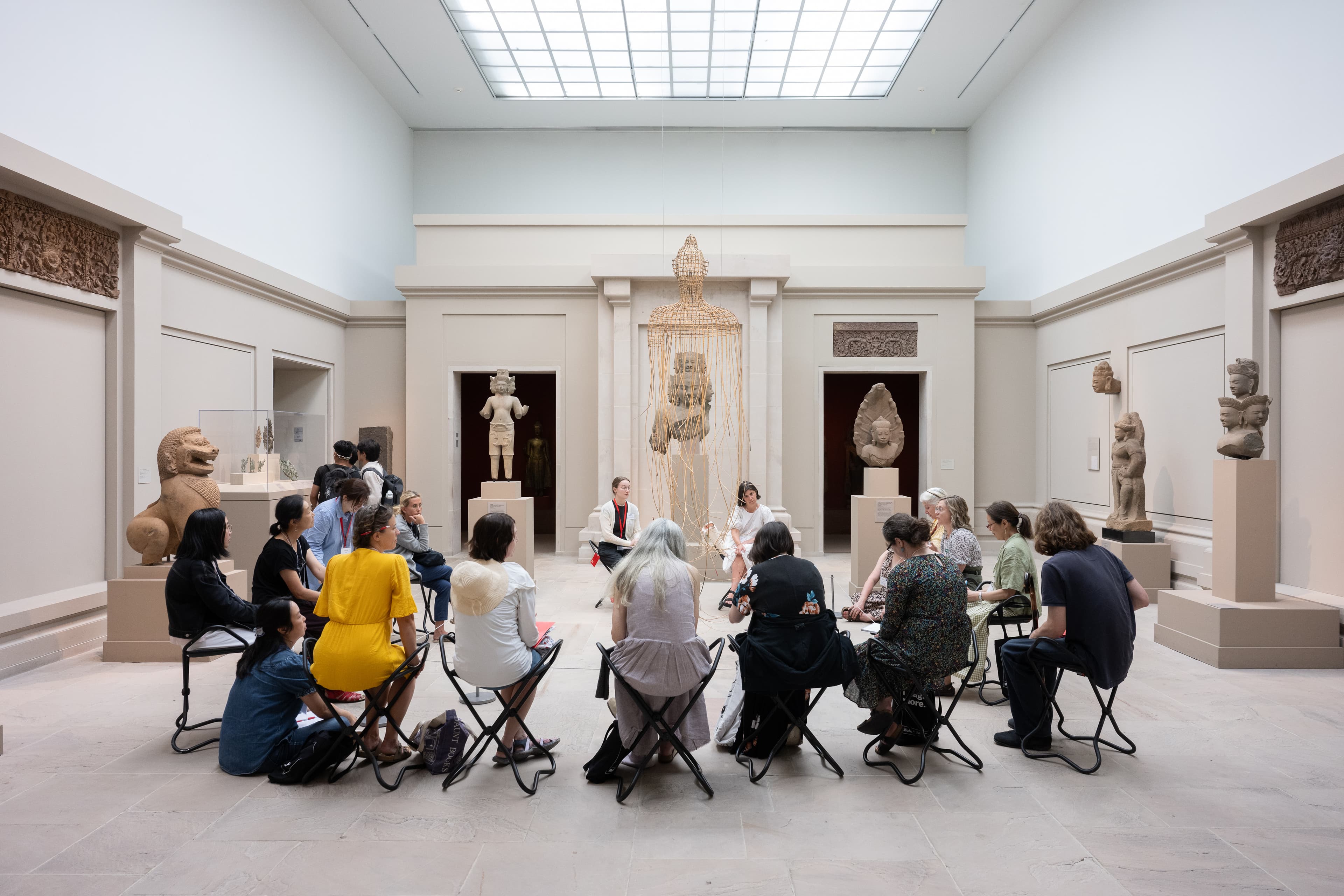 A group of teachers in a large gallery space, seated and facing an artwork