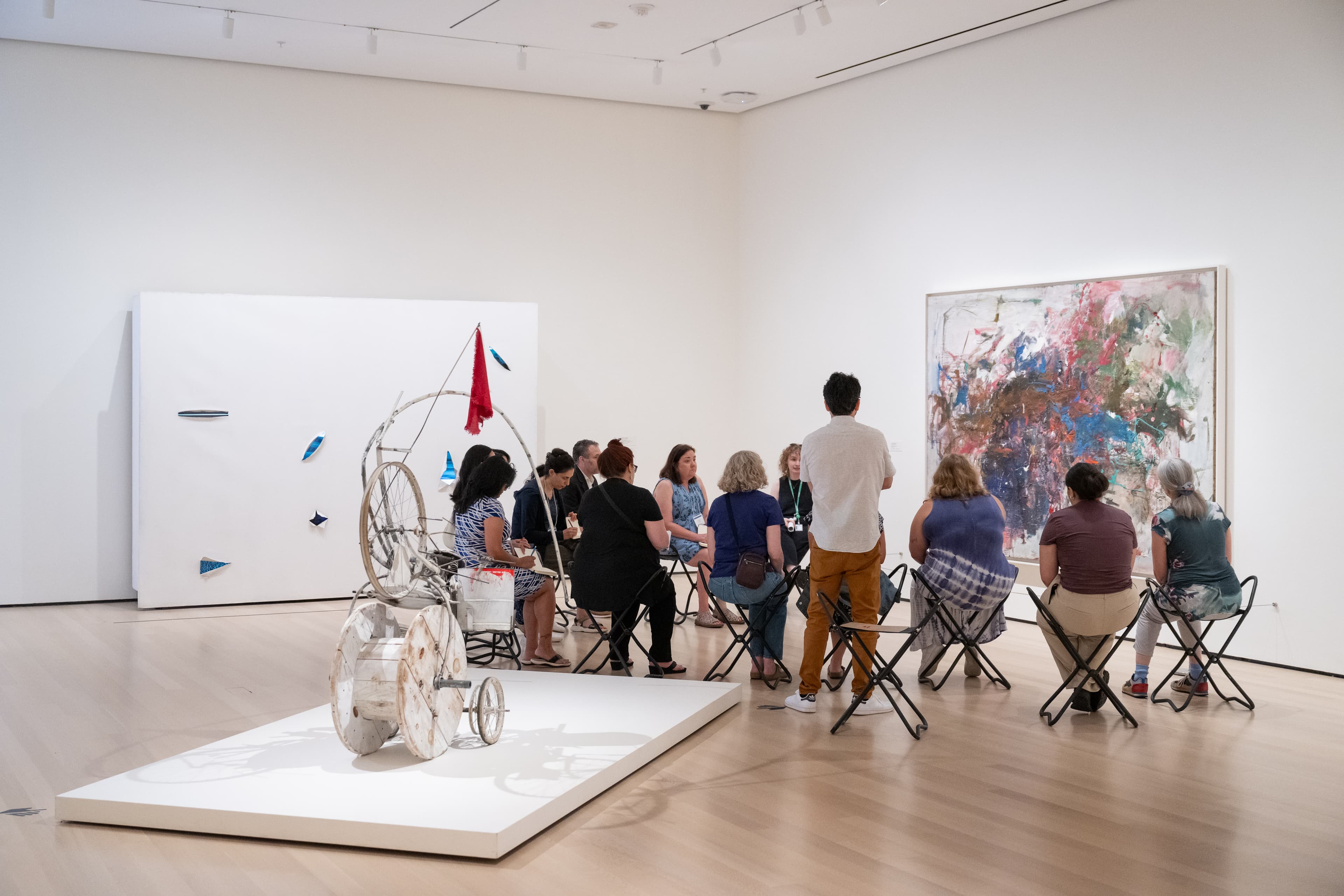A group of teachers in a large gallery space, seated and facing an artwork