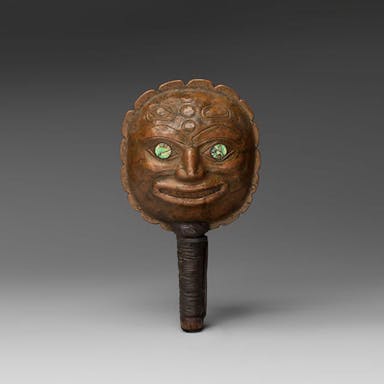 A wooden rattle with green eyes