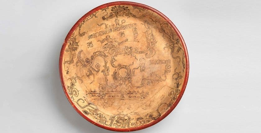 Cream plate with a rim painted with watery motifs in black, including swirls, registers of droplets, and waterlily vegetation.