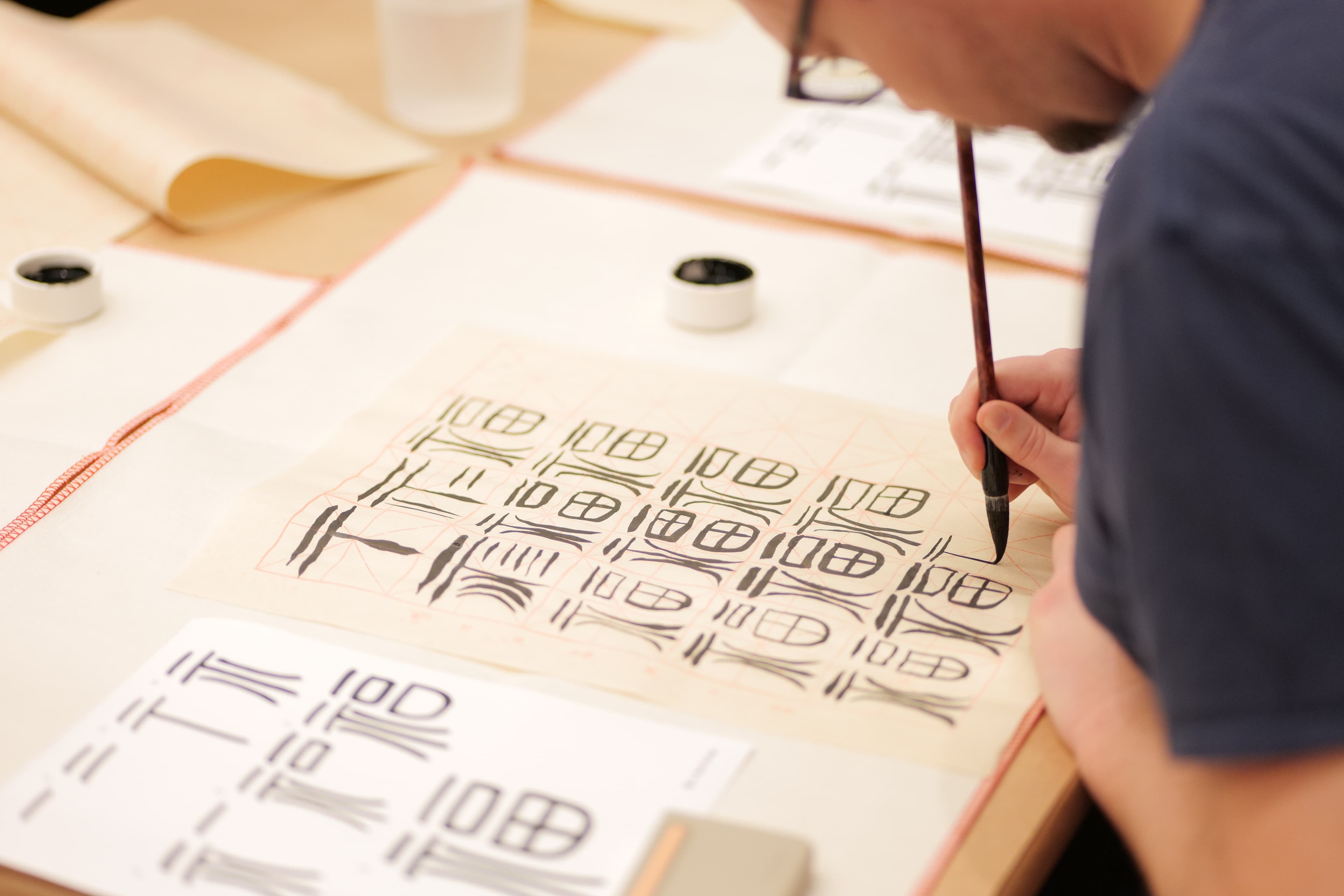Program participant practicing Chinese calligraphy using a brush and ink