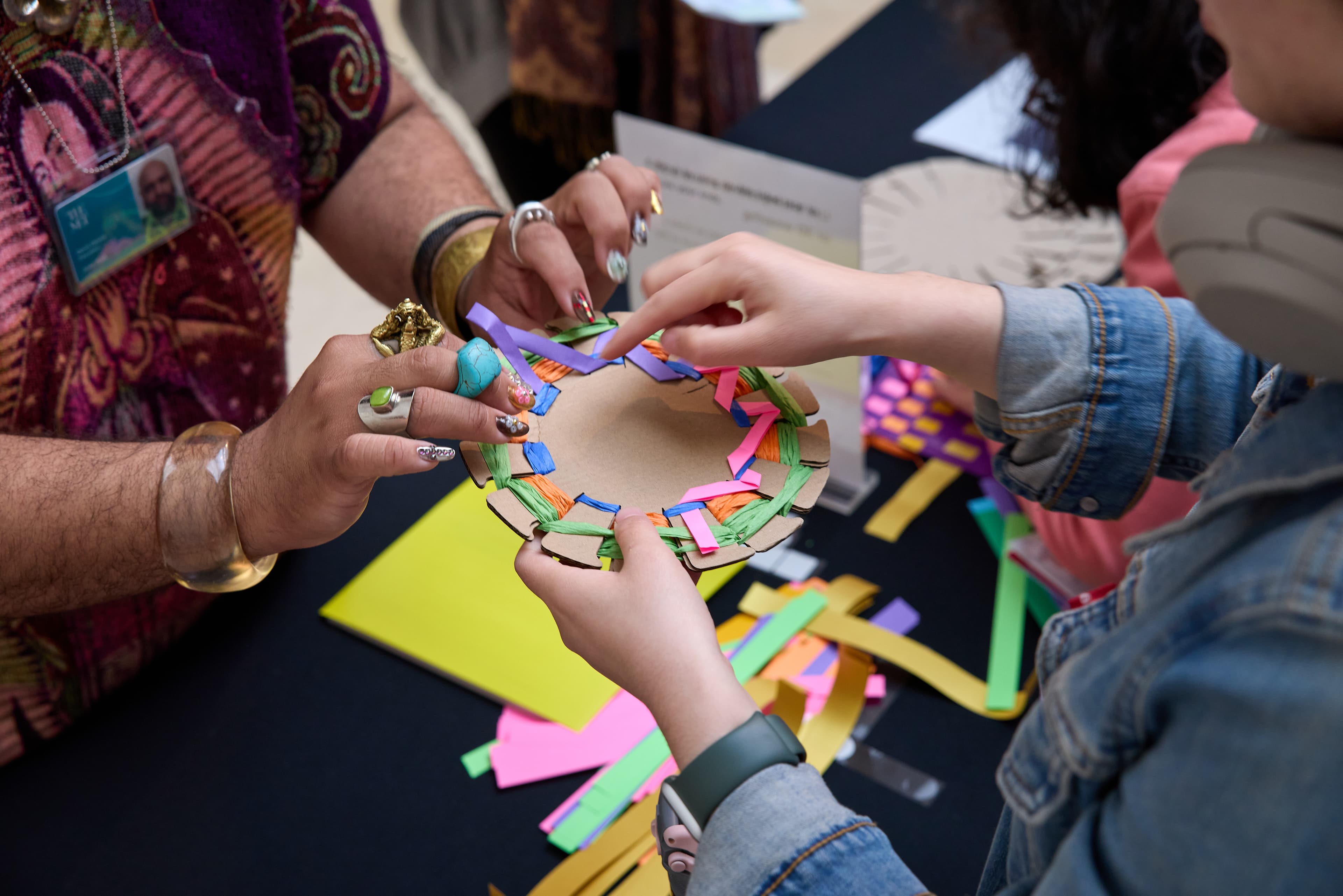 Hands of program instructor and program participant who are collaborating on a basket-making project.