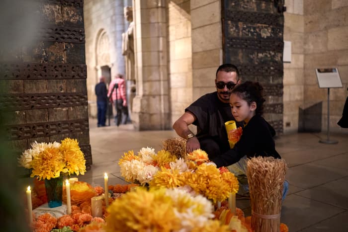 A father and child placing a candle in front of an alter with yellow flowers